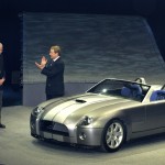 William Clay Ford Jr. (R) and J Mays, VP, Design and Chief Creative Officer (L) applaud Carroll Shelby (C) following the introduction of the Ford Shelby Cobra Concept January 4, 2004 at the North American International Auto Show in Detroit, Michigan